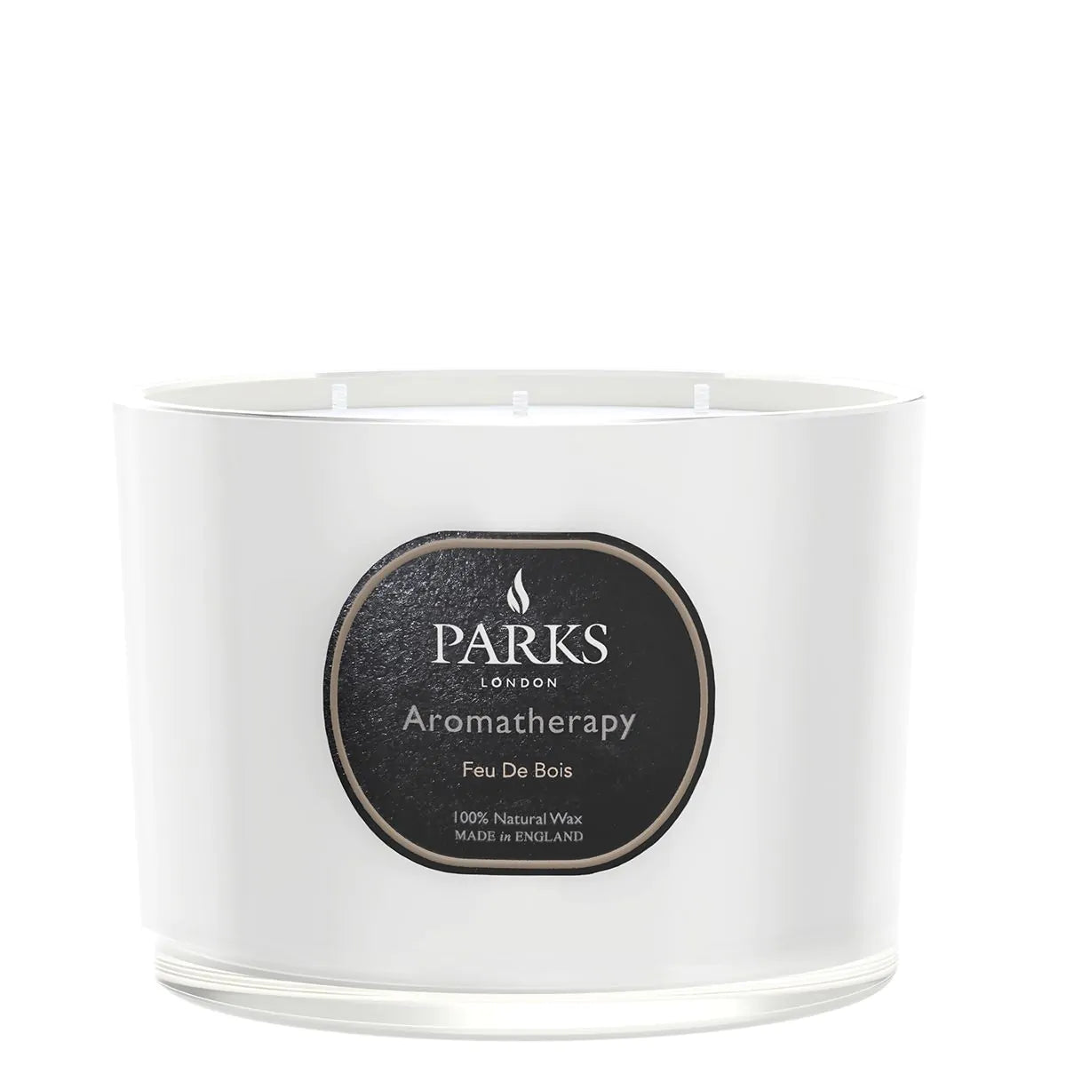 A white, glass-enclosed three-wick candle with a label that reads 'PARKS Aromatherapy Feu De Bois'.