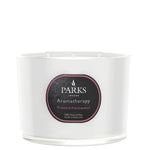 A white, glass vessel candle with a label that reads 'PARKS Aromatherapy Rhubarb & Pink Grapefruit'. The candle is unlit and appears to be a luxury product.